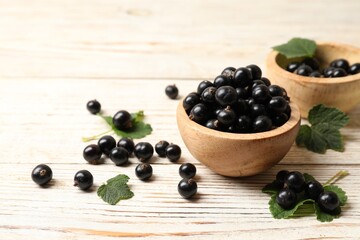 Ripe blackcurrants and leaves on light wooden table. Space for text