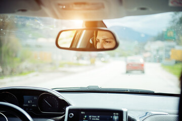 Attentive eyes of a female driver in the rearview mirror while driving, traveling by car