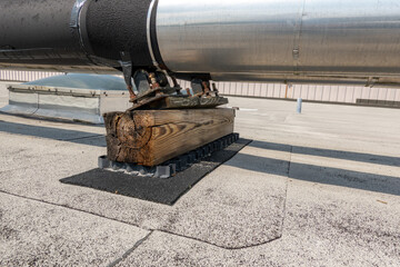 Roof mounted industrial insulated HVAC pipes on gray roof and wooden supports.	