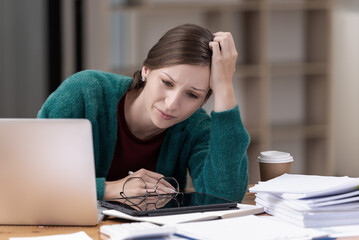 Businesswomen are stressed with work in front of a laptop and paper documents in the office.
