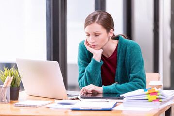 Fototapeta premium Businesswomen are stressed with work in front of a laptop and paper documents in the office.