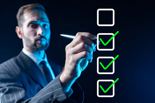 Businessman fills in checkbox. Man ticks box. Guy draws on virtual screen. Concept of maintaining step-by-step plan. Checkbox on invisible display. Businessman in formal suit. Selective focus