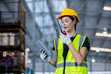 women engineer holding walkie talkie and tablet quality control standing at machine of factory warehouse. professional engineering machinery workshop.