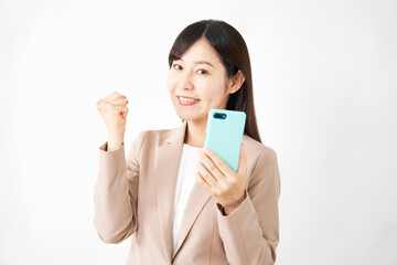 スマートフォンを持ってガッツポーズをするミドルエイジのビジネスウーマン　白背景