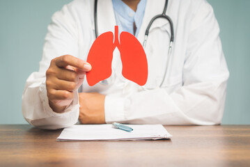 Physician holding a lung shape symbol while sitting at a table in the hospital.