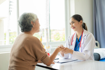 Family doctor examining smiling asian old woman using stethoscope at hospital An old woman talks and consults with a doctor about osteopathy. Health and wellness concept