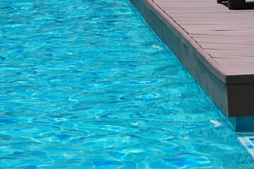 Fototapeta na wymiar surface of blue swimming pool with brown wood balcony, freshness water background