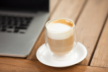 Coffee cup on the table in coffee shop as blur laptop background.