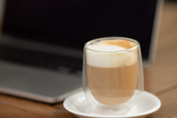 Coffee cup on the table in coffee shop as blur laptop background.