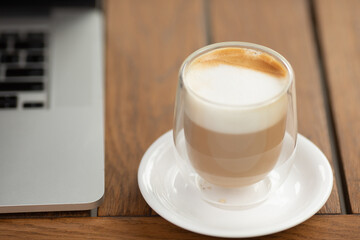 Coffee cup on the table in coffee shop as blur laptop background.