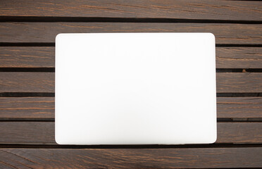 Grey metallic laptop closed on wooden background. Communication network. Silver metal surface....