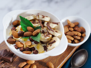 Almond banana salad with chocolate and milk in white plate. Healthy nutritious breakfast. Top view. Still life. Background.