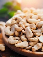 Cashew nuts are poured into wooden plate on table. Close-up still life. Advertising photo for sale of shelled cashews. Background.