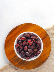 Rose hips in bowl on wooden stand. Top view with copy space. Preparation of layout for sale of dried rose hips in online store or marketplaces. Vertical photo.