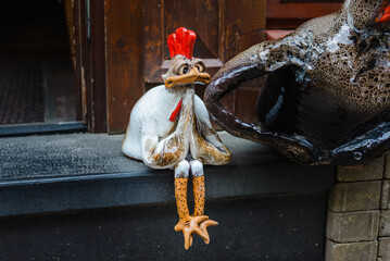 a small decorative rooster prays on a city street.Gritty and funny rooster chick asks a passerby for alms. © ARVD73