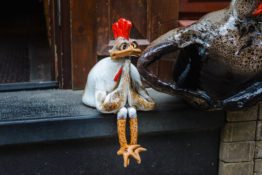 a small decorative rooster prays on a city street.Gritty and funny rooster chick asks a passerby for alms.