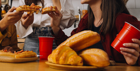 Laughing group of diverse young woman hanging out at home together and eating pizza