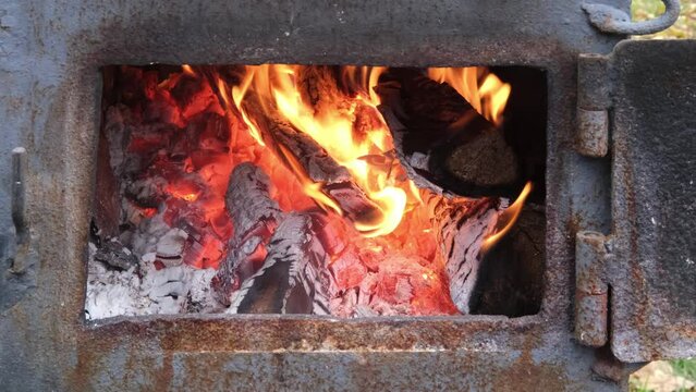Open vintage wood stove in detail. The fire burns in the old furnace, firebox, kindling fire in the furnace. Warming warmth. Close-up of a stove with an open door