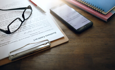 Fototapeta premium Business contract document with eyeglasses, pen and mobile phone on desk office prepared for signing documents for make a new business contract or insurance related business