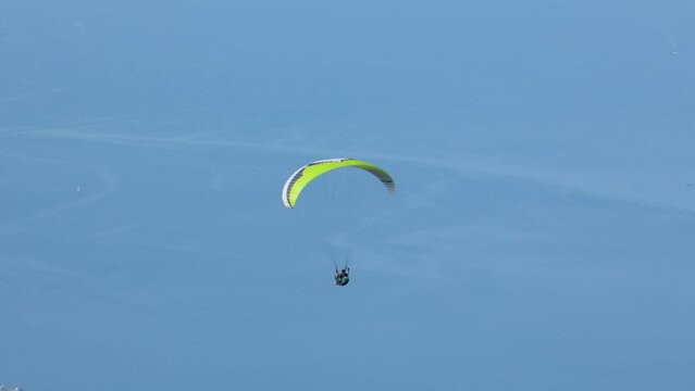 Tracking shot of single man paragliding above lake Garda in Italy in summer