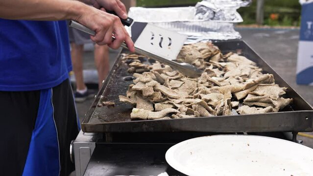 Gyro meat, lamb, cooking on a large flattop grill.