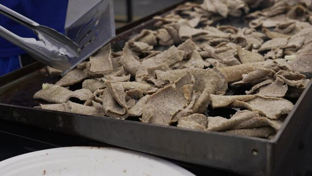 A person grilling meat for Gyros, a Greek dish.