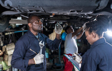 auto black mechanic man and woman working underneath car with asian technician background