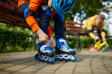 Selective focus of grandson and grandfather putting on roller skates