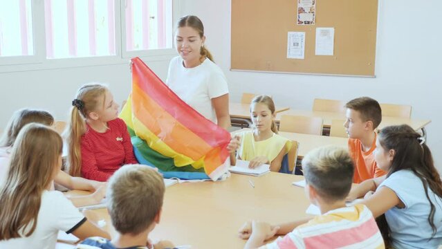 Positive female teacher explaining lgbt theme to children during lesson in class in secondary school. High quality 4k footage