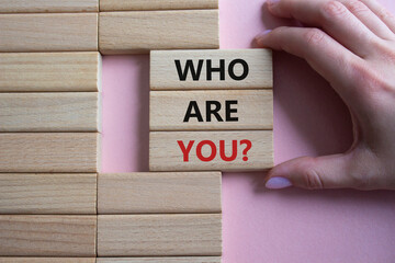 Who are You symbol. Concept words Who are You on wooden blocks. Businessman hand. Beautiful pink...