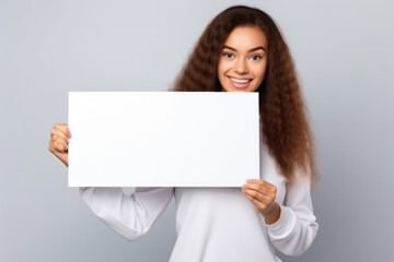 Naklejka premium Happy young woman holding blank white banner sign, isolated studio portrait .