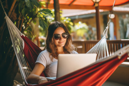 Woman using laptop outdoor. Young beautiful girl in a hammock and working on computer. Freelance, summer, enjoy life, student lifestyle, distance studying, travel vacations.