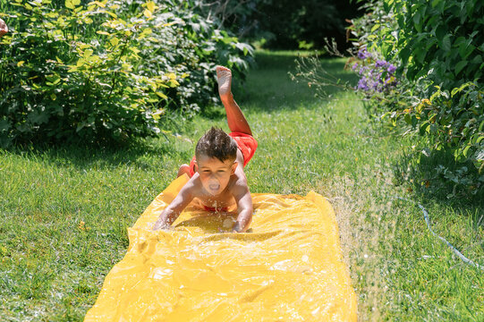 Little boy jumping on water slide 