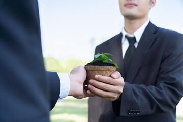 Business people holding plant as concept of eco company committed to corporate social responsible,...