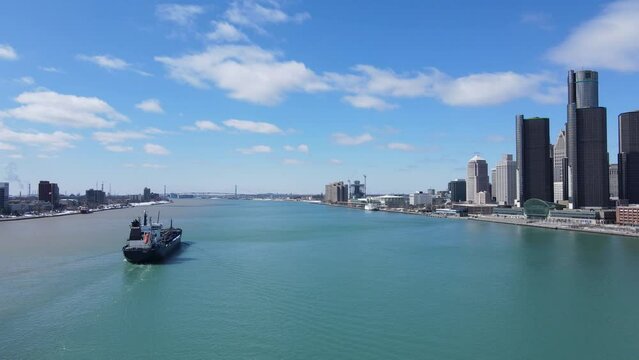 Cargo ship sailing near majestic skyline of Detroit, aerial drone view