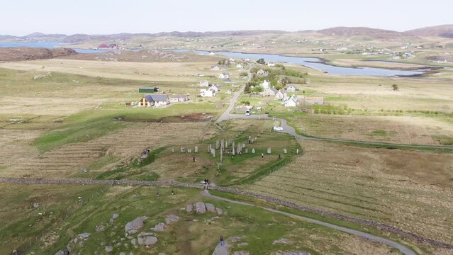 Wide angle drone shot of the Callanish Standing Stones on the Isle of Lewis, part of the Outer Hebrides of Scotland. Filmed on a sunny, summers day. Tourists and visitors are visible.