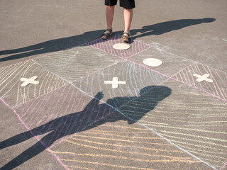 Unidentified children play hopscotch, tic tac toe on playground