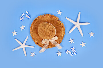 White starfish, summer straw hat and sandals on blue background
