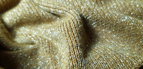 Wavy shimmering surface of mustard golden fabric with lurex, in convex folds (macro, knitwear,...