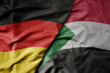 big waving realistic national colorful flag of germany and national flag of sudan .