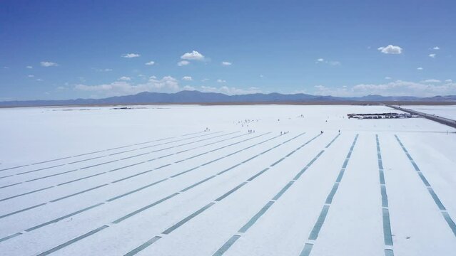Forward aerial of people by rows of water at salt flats in Argentina
