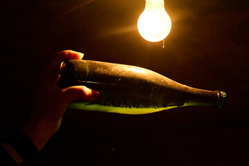 Person holding an old wine bottle against light