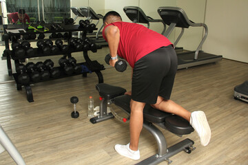 Dark-haired 40-year-old Latino man exercises weights in the gym to avoid overweight, diabetes and...