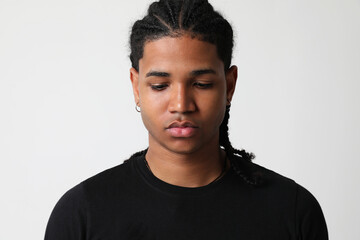 Dark-skinned young man posing in the studio and looking down. Mind set concept.
