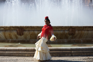 Young black woman dressed as a flamenco gypsy in a famous square in Seville, Spain. She is wearing...