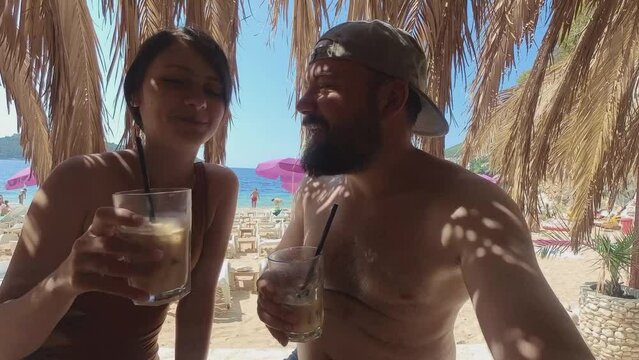 Female and male model drinking ice coffee on the beach in Dubrovnik