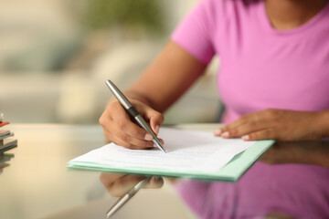 Black woman hand filling form on a desk - 629434498