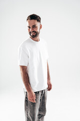 Fototapeta premium Portrait of handsome smiling stylish hipster lambersexual model. Sexy man dressed in white T-shirt and jeans. Fashion male isolated on white background in studio