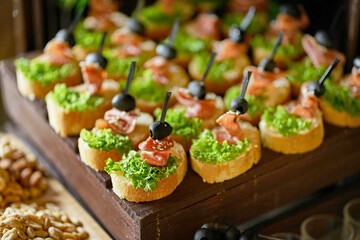 Buffet with sandwiches with fish, olives and greens.