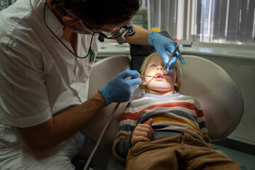 Dentist examining patient's teeth with dental equipment at clinic